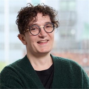 Bee Wanono-Samuel in glasses and a green jumper, in front of a window