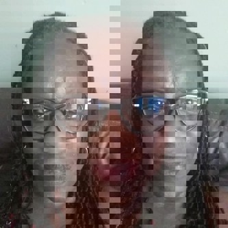 Selfie of Elaine Mills with glasses smiling at the camera.