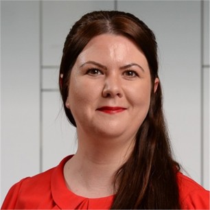 Andrea Lynch in a red top,  in front of a geometric glass background