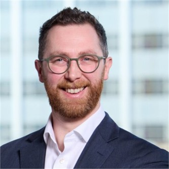 Andrew Moore in glasses and a dark jacket, in front of a window