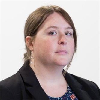 Charlotte Shaughnessy in a black jacket, in front of a pale background