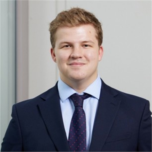 Archie Eke in a dark suit and tie, in front of a pale background