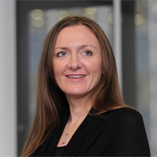 Adele Evans in a black jacket in front of a window