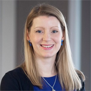 Anna Moore in a blue top, in front of a grey background