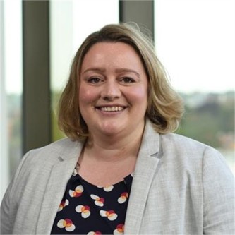 Charlotte bull in a grey jacket, in front of a window