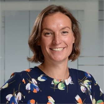 Claudia Gilham in a navy floral top, in front of a geometric glass background