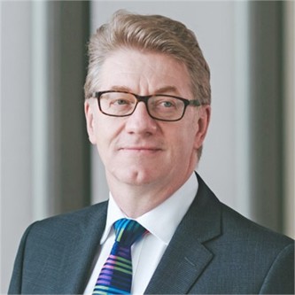 Andrew Ray in a grey suit and tie, in front of a grey background